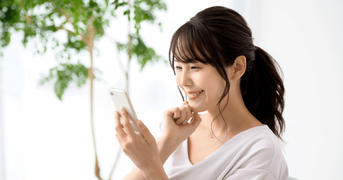 笑顔でスマホを見る女性