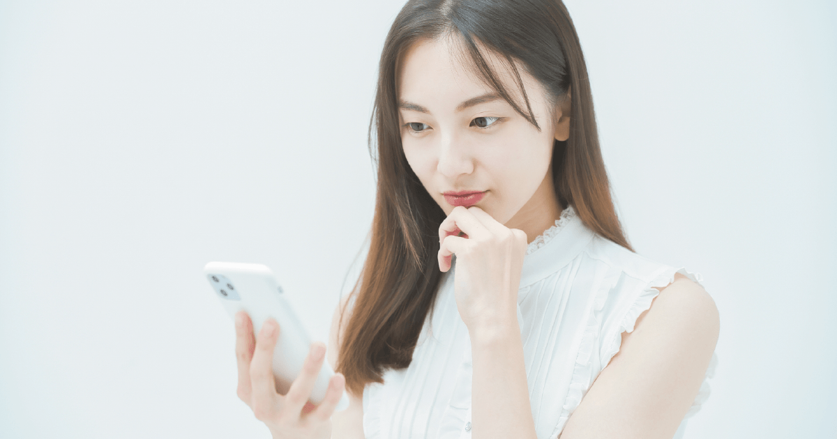 スマホを見ながら考える女性