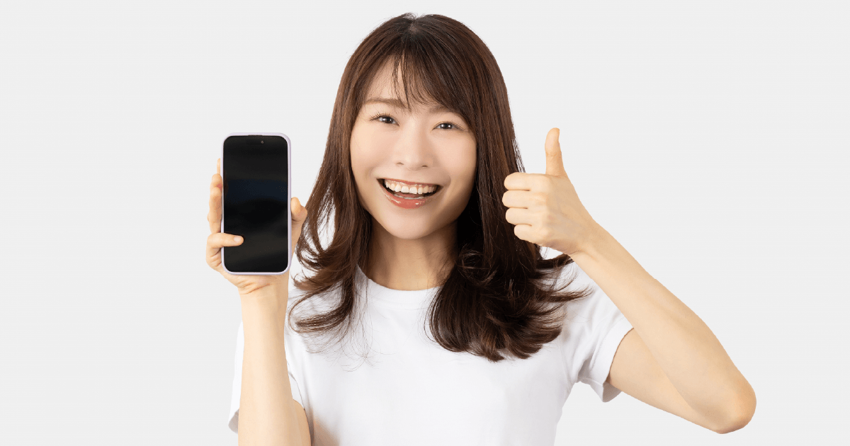 スマホを持ってGoodポーズをする女性