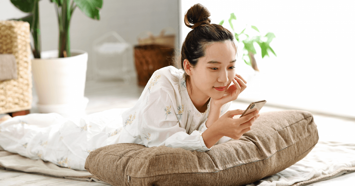 寝転びながらスマホを操作する女性