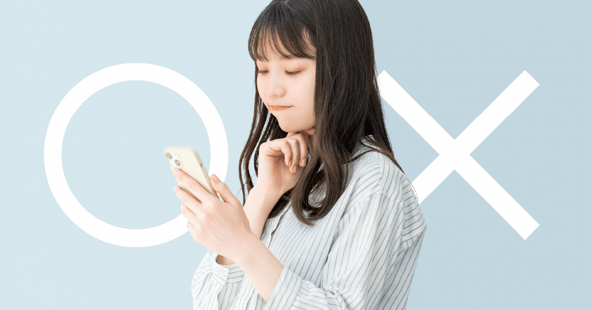 スマホを見ながら○か×か考える女性