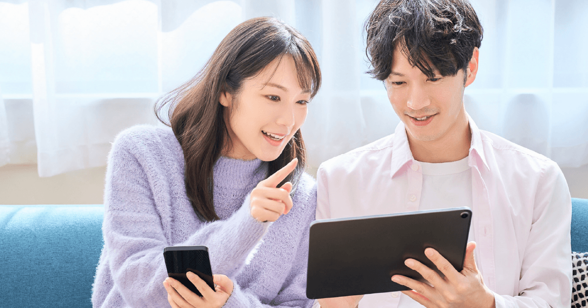 スマホとタブレットを見ながら話す男性と女性